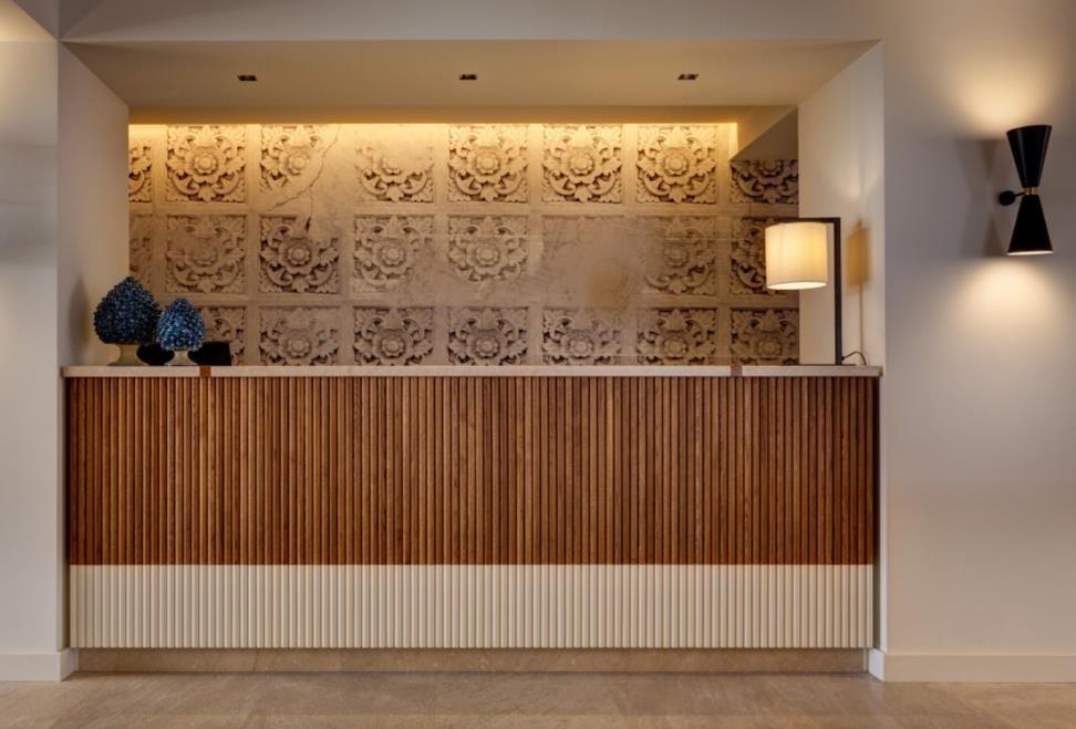 Reception counter in slatted timber below a carved relief wall
